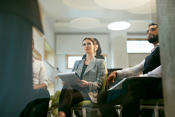 A group of students in professional attire sitting in a semi-circle and listening attentively during a seminar.